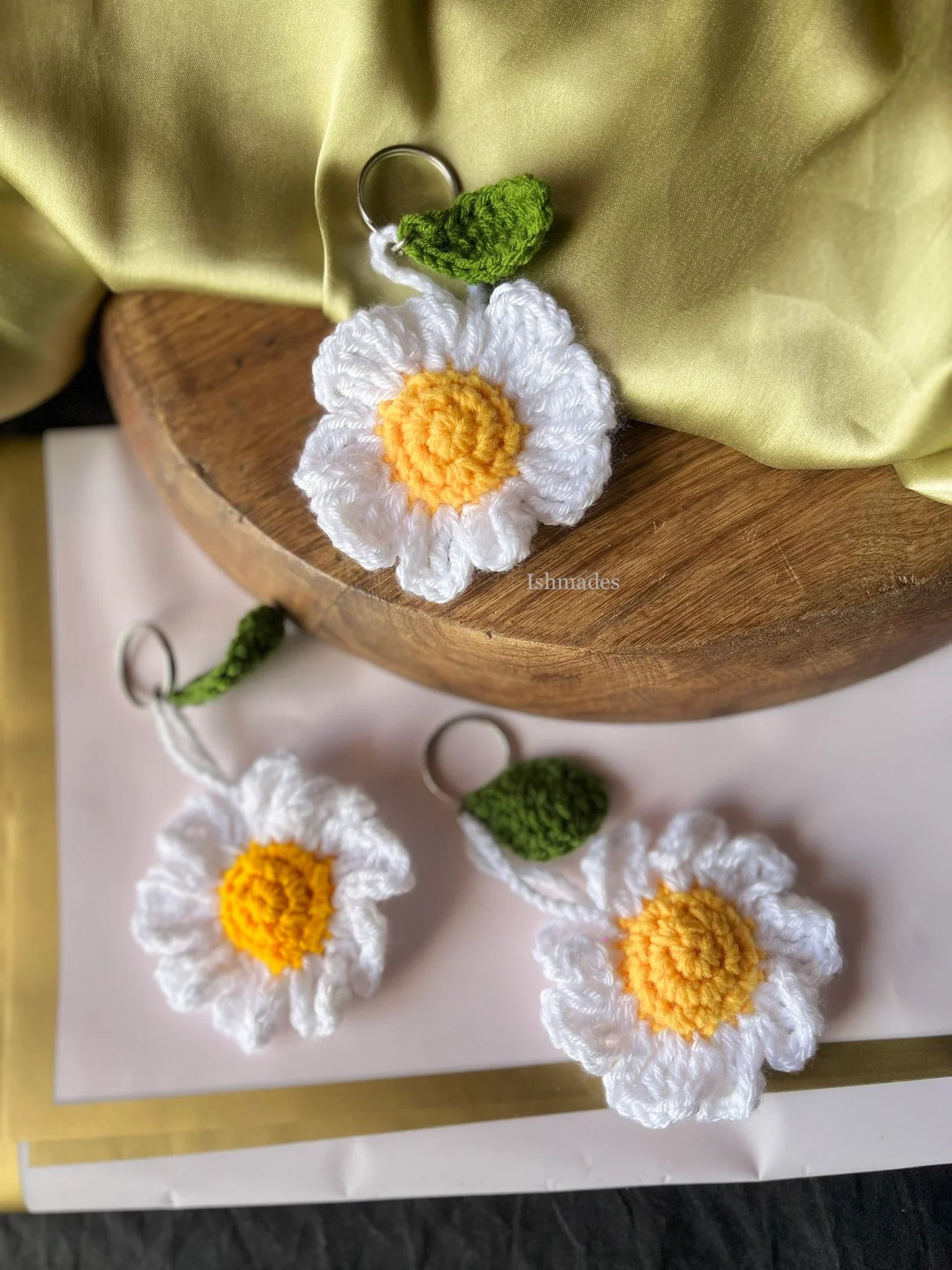Handmade crochet daisy flower keychains with yellow centers and white petals on display