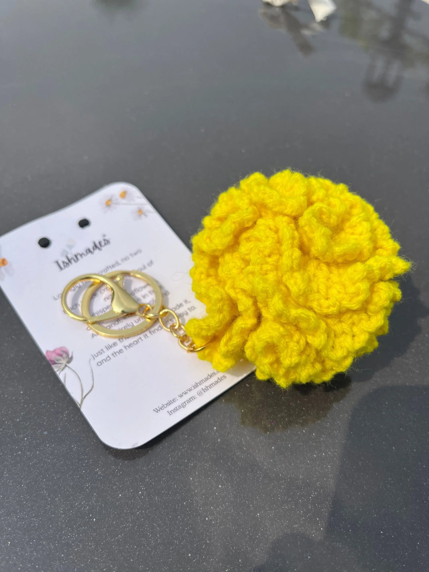 Yellow crochet flower keychain with gold clasp on a display card