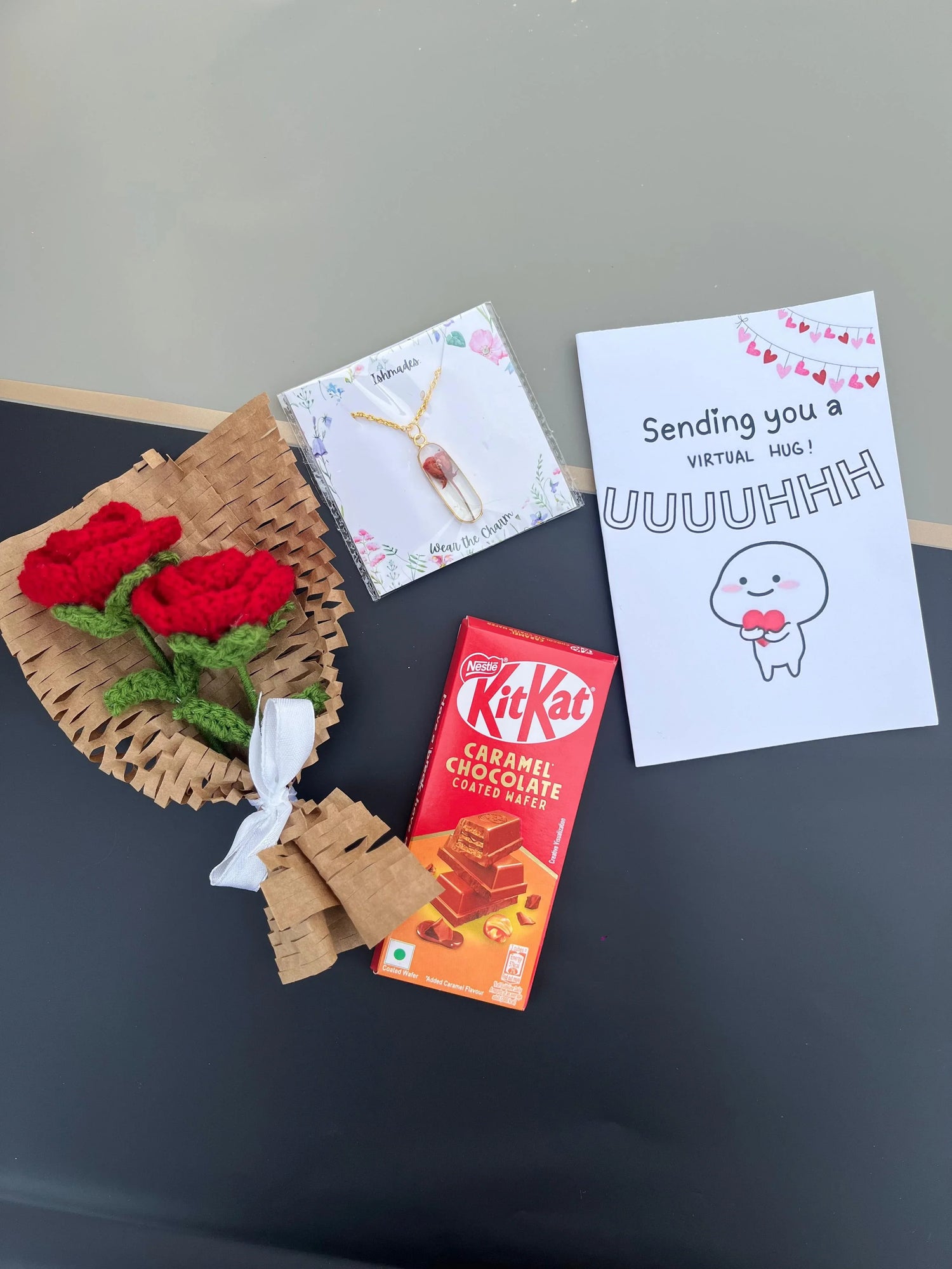 Gift set with a crochet rose bouquet, crystal pendant necklace, KitKat caramel chocolate, and greeting card.