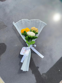 Handmade crochet flower bouquet with yellow, white, and beige blooms wrapped in white paper