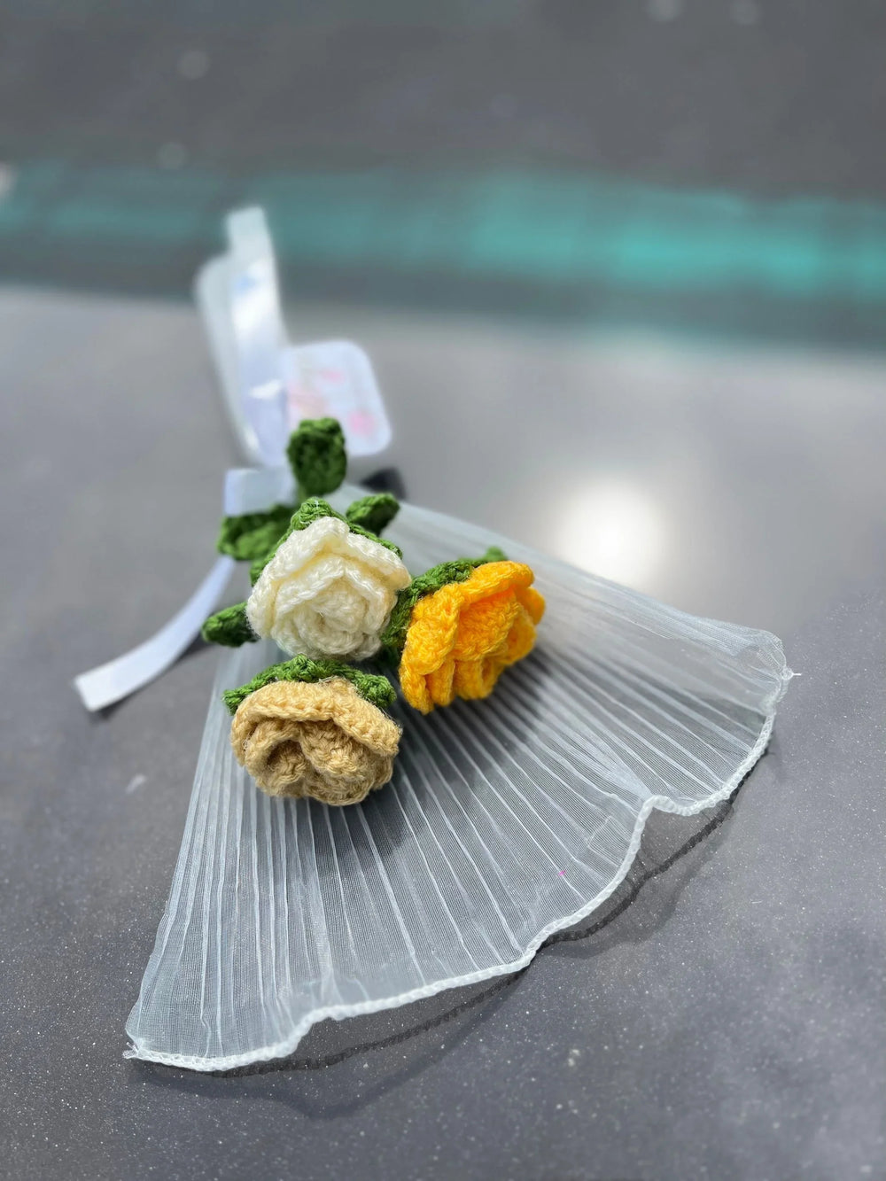 Handcrafted crochet flower bouquet with yellow, cream, and beige roses on sheer fabric