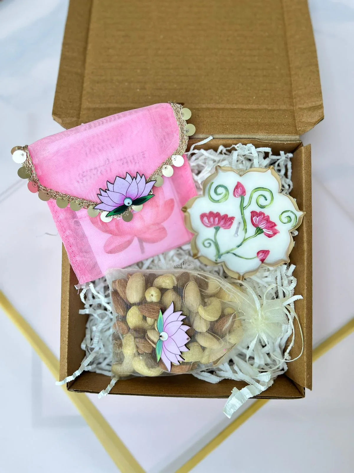 Gift box with pink pouch, decorated cookie, and assorted nuts in organza bag
