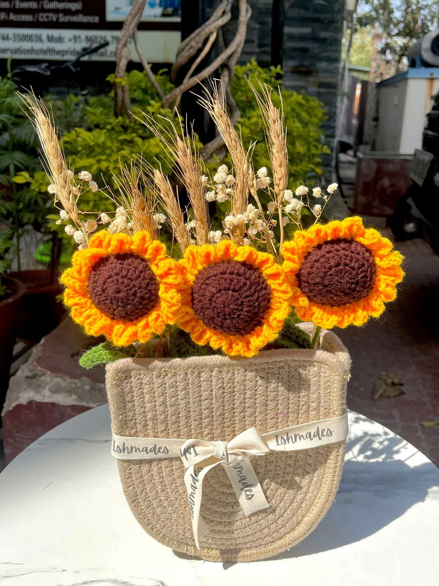 Handmade crochet sunflowers in a woven basket with ribbon, outdoor setting
