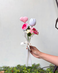 Hand holding a bouquet of crochet flowers and heart with ribbon, gift arrangement